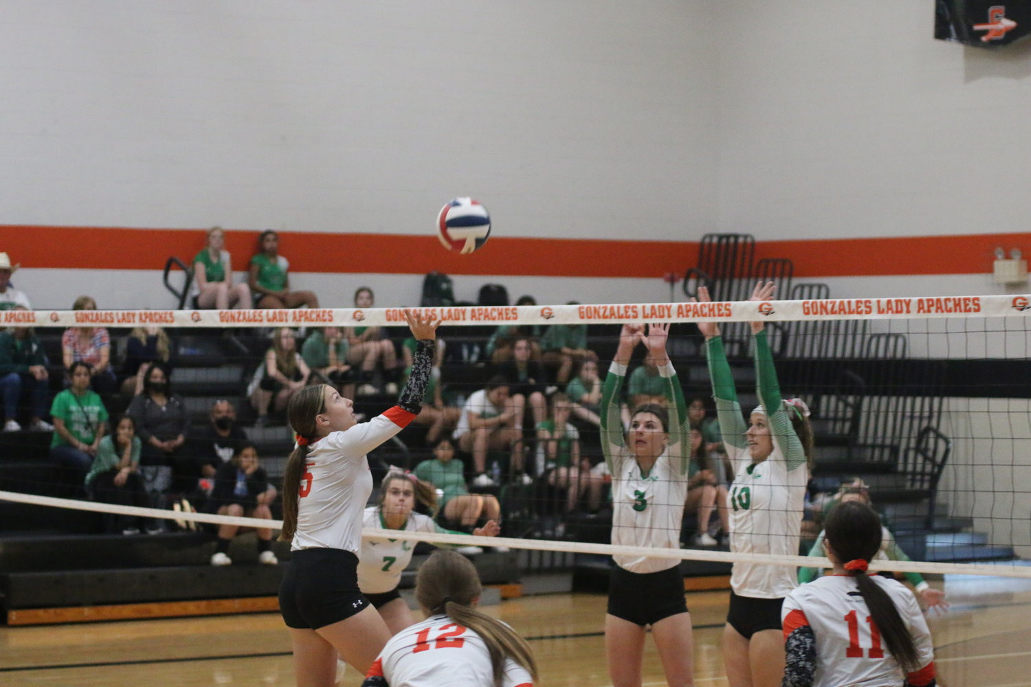 Sydney McCray (5) tries to catch Pleasanton off balance with a dink while Macy Sample (12) and Tara Lester (11) look on.