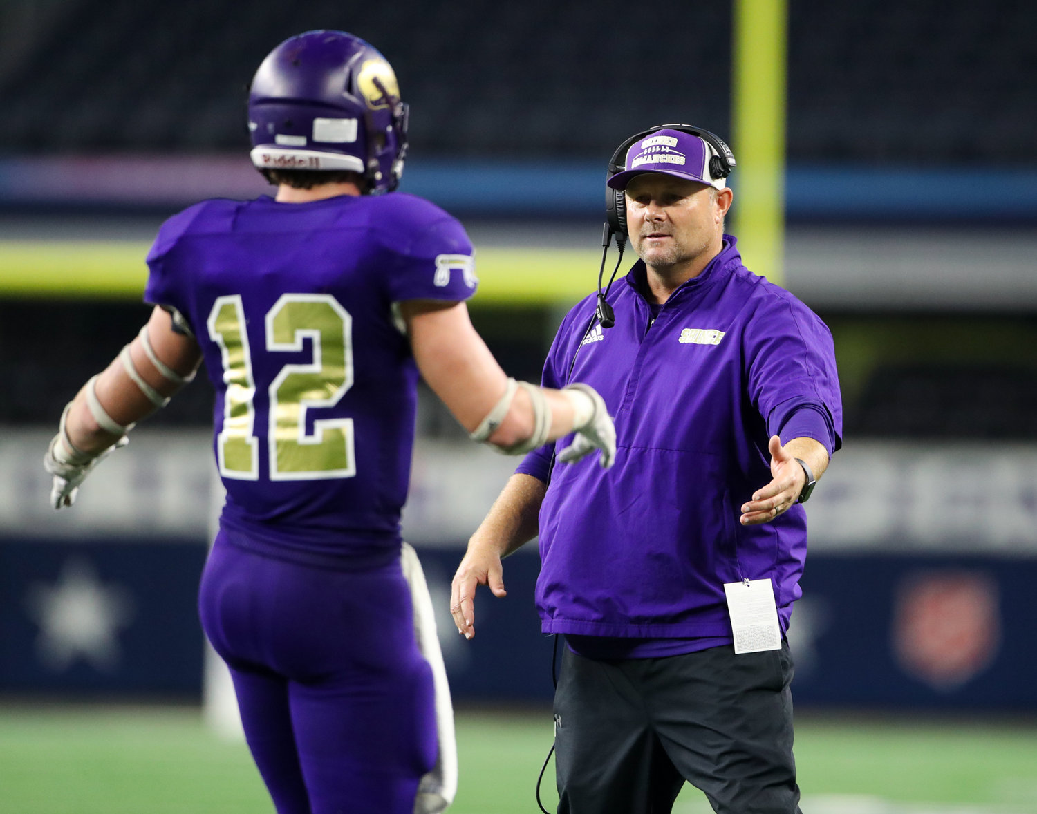 Shiner Comanches head coach Daniel Boedeker congratulates senior Tyler Bishop (12) after a touchdown during the Class 2A Division I state football championship game between Shiner and Hawley on December 15, 2021 in Arlington, Texas.